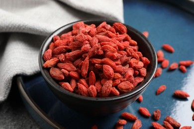 Photo of Dried goji berries in bowl on table, closeup