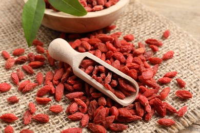 Dried goji berries and scoop on table, closeup