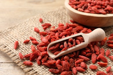 Dried goji berries and scoop on wooden table, closeup