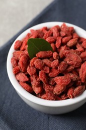 Dried goji berries in bowl on grey table, closeup