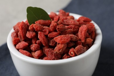 Photo of Dried goji berries in bowl on table, closeup