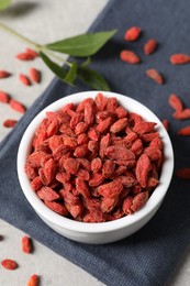 Dried goji berries in bowl on grey table, above view