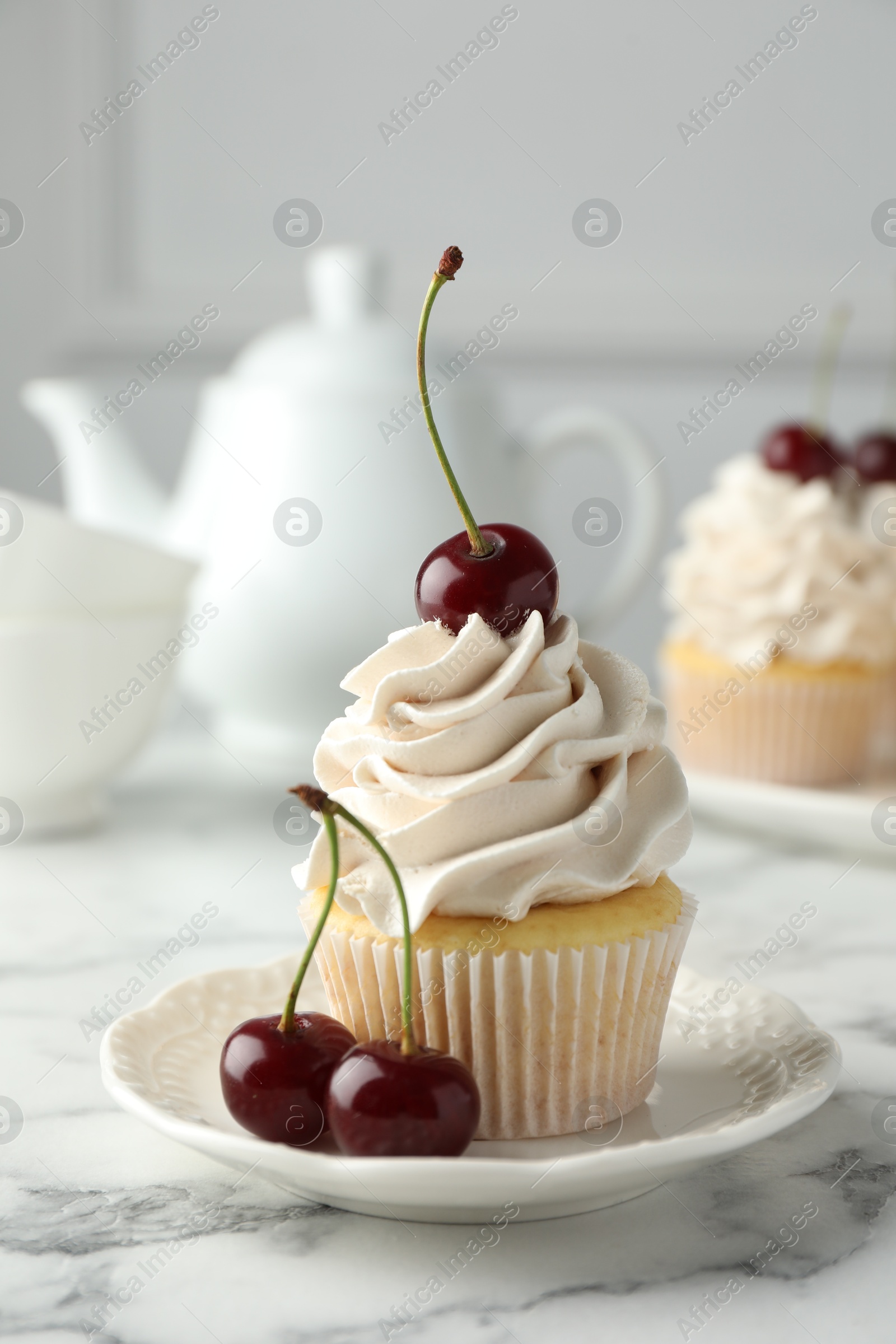 Photo of Delicious cupcake with cream and cherries on white marble table