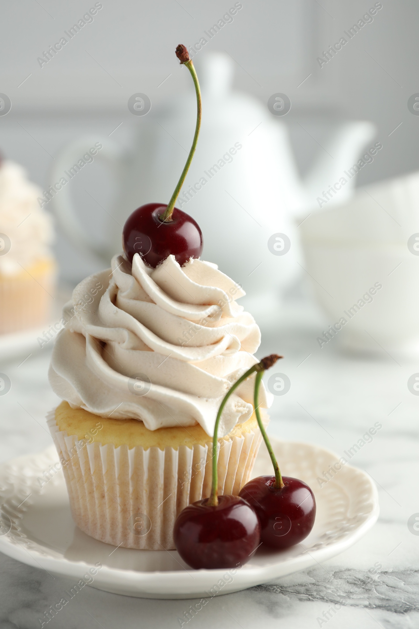 Photo of Delicious cupcake with cream and cherries on white marble table