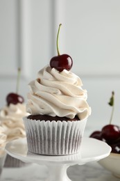 Photo of Delicious cupcake with cream and cherry on table