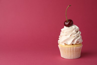 Delicious cupcake with cream and cherry on red background, space for text