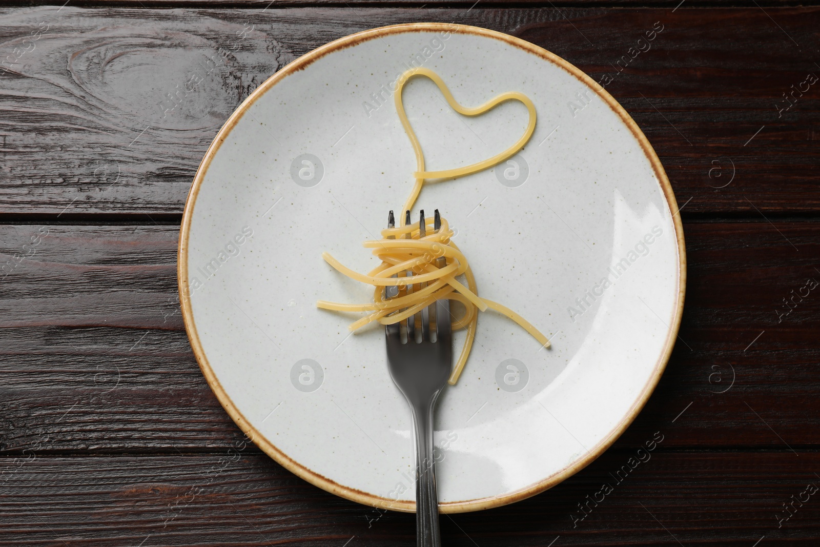 Photo of Heart made of tasty spaghetti and fork on wooden table, top view