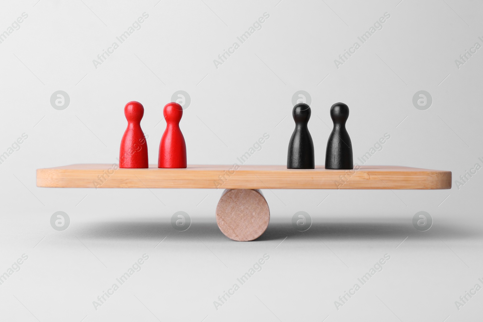 Photo of Equality concept. Seesaw scale with game pieces on light background