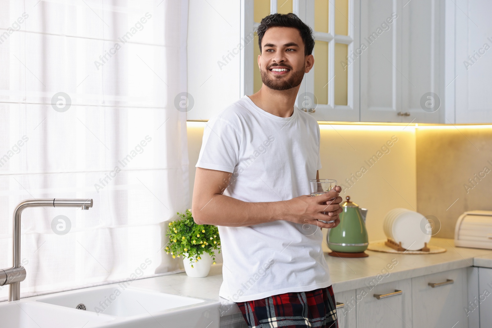Photo of Happy man with glass of water in kitchen at morning