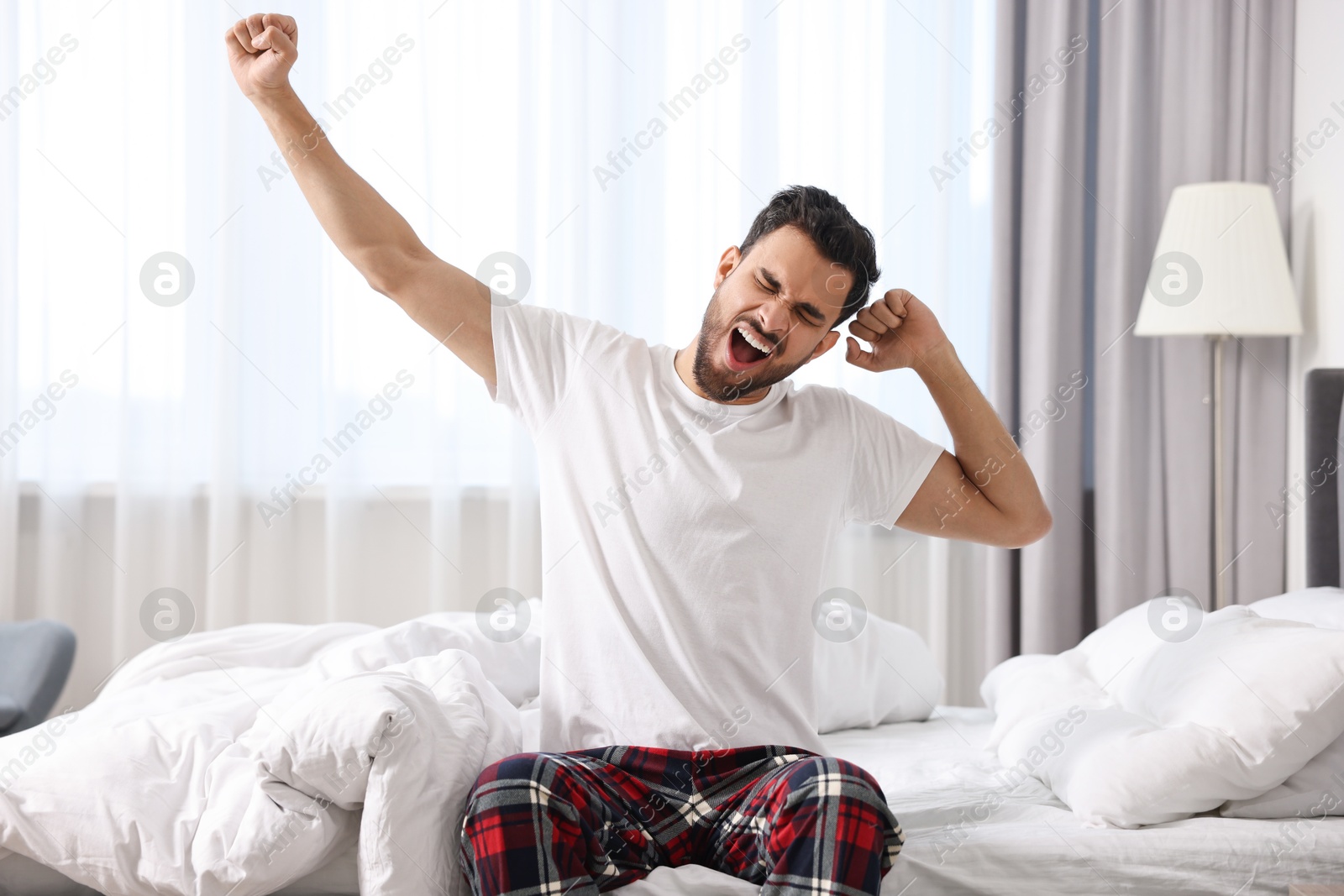 Photo of Man stretching and yawning on bed at morning