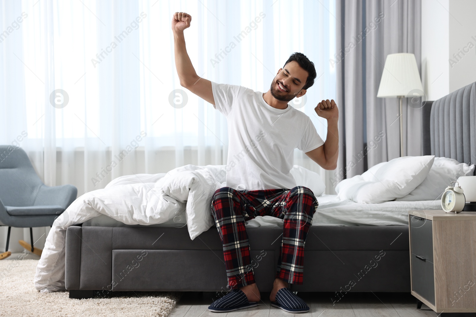 Photo of Good morning. Happy man stretching on bed at home