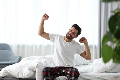Photo of Good morning. Happy man stretching on bed at home