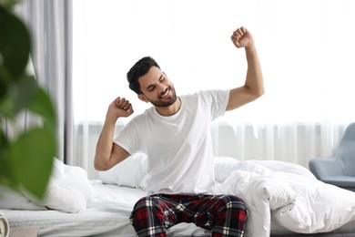 Good morning. Happy man stretching on bed at home