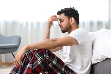 Man suffering from headache with glass of water at morning