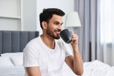 Photo of Happy man drinking coffee on bed at morning