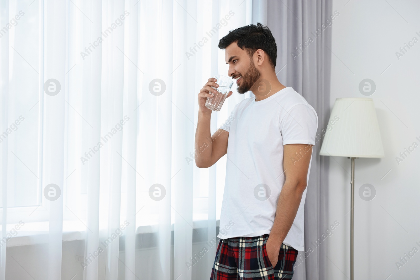 Photo of Happy man with glass of water at morning. Space for text