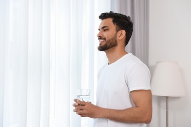 Photo of Happy man with glass of water at morning. Space for text