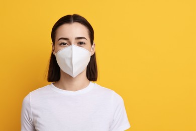 Woman in respirator mask on orange background, space for text