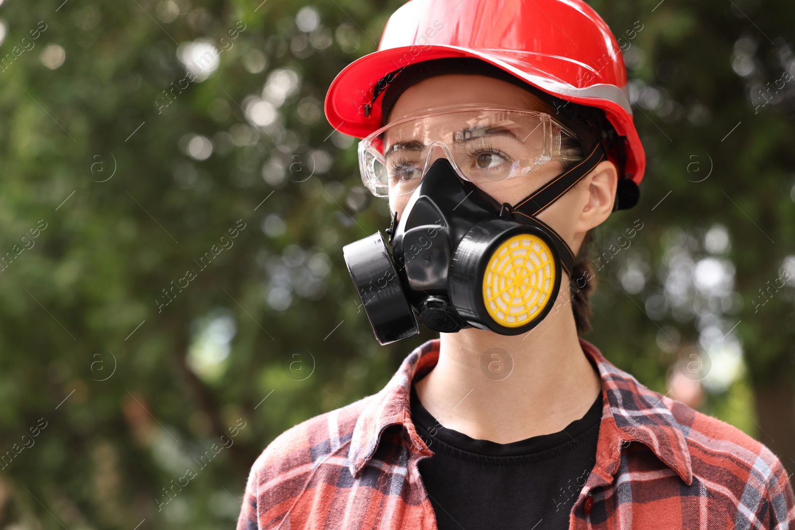 Photo of Woman in respirator mask, protective glasses and helmet outdoors