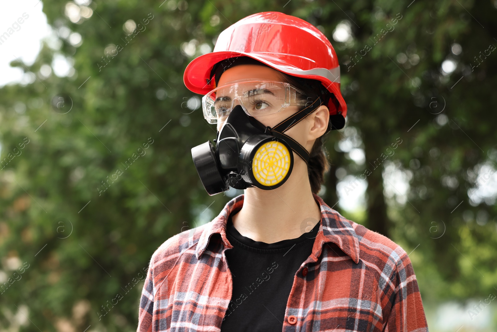 Photo of Woman in respirator mask, protective glasses and helmet outdoors