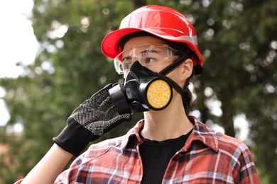 Photo of Woman in respirator mask, protective glasses and helmet outdoors