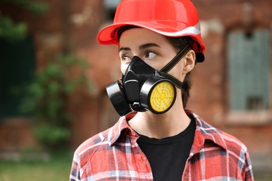 Woman in respirator mask and helmet outdoors. Protective equipment