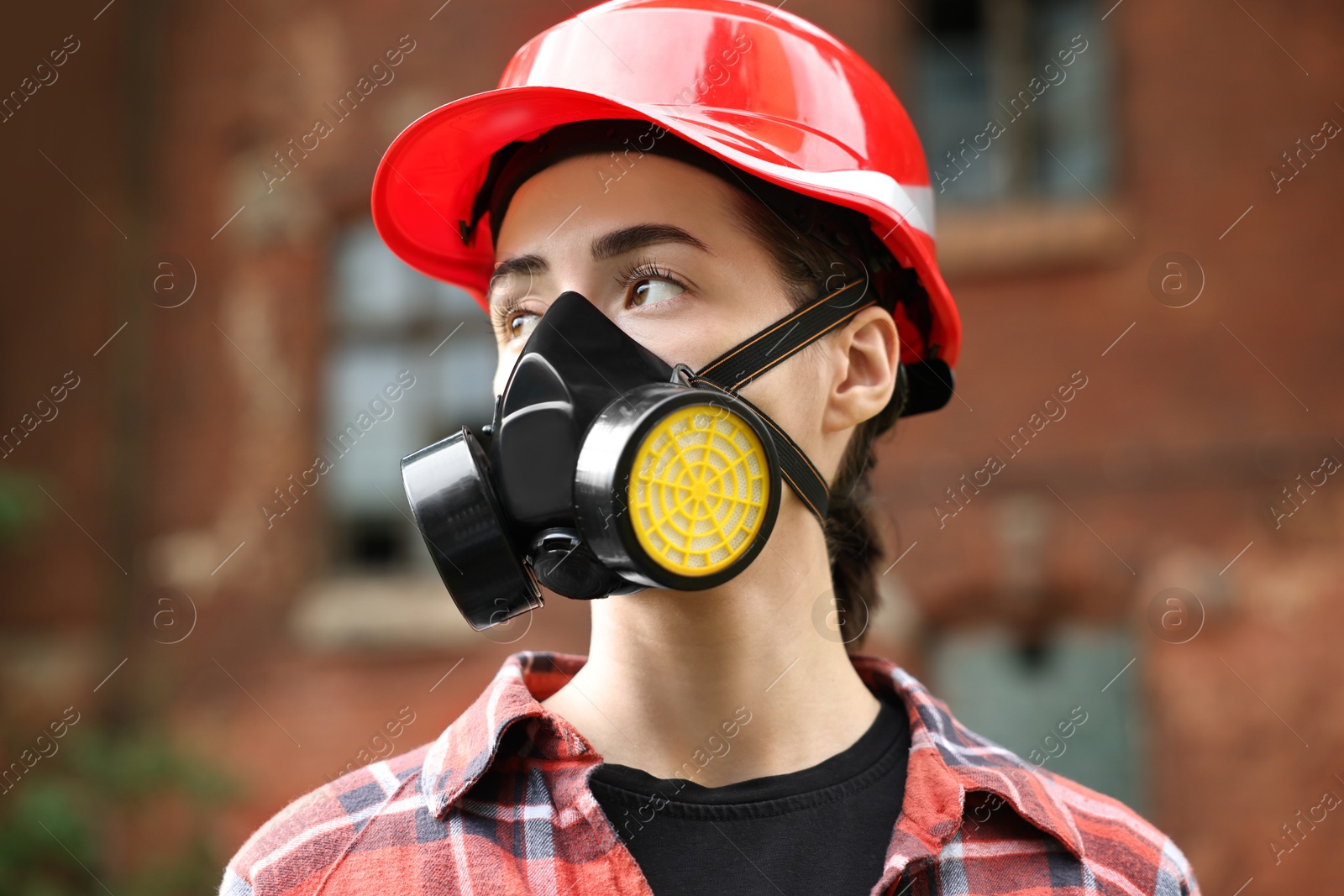 Photo of Woman in respirator mask and helmet outdoors. Protective equipment