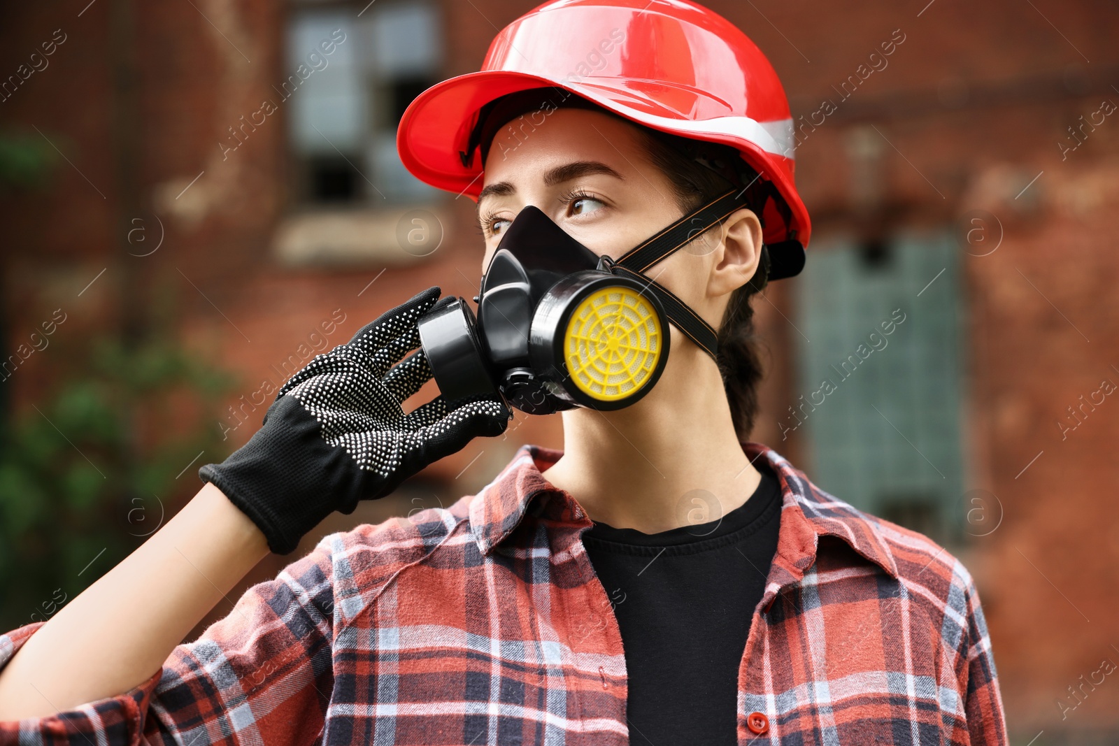 Photo of Woman in respirator mask and helmet outdoors. Protective equipment