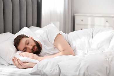 Handsome young man sleeping in bed at morning