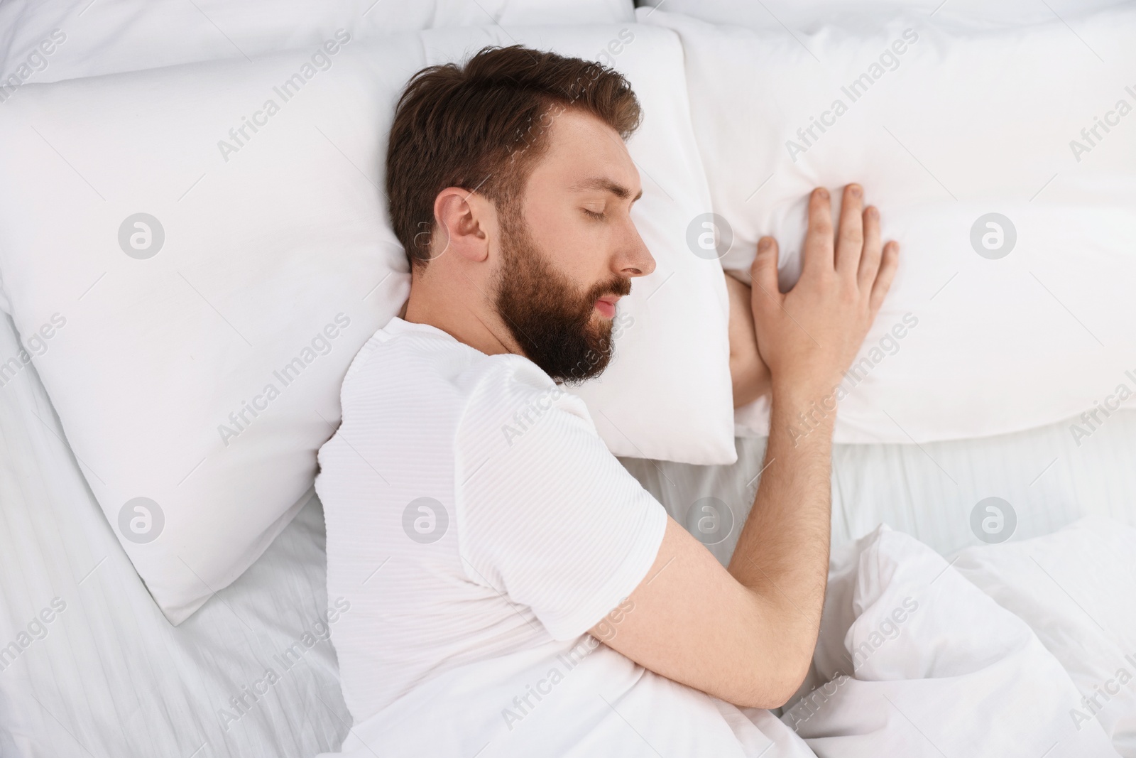 Photo of Handsome young man sleeping in bed at morning, top view