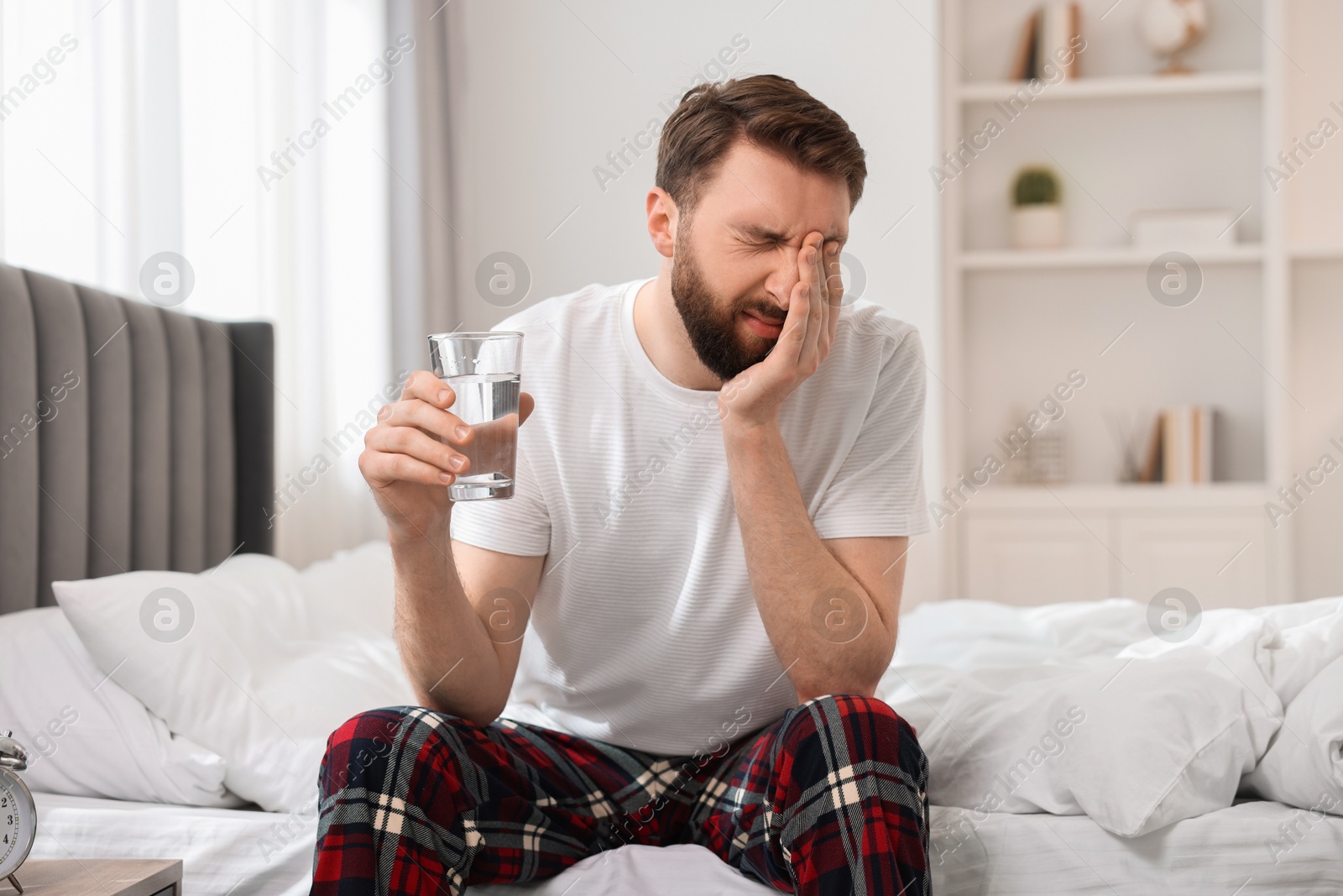 Photo of Young man suffering from headache on bed at morning