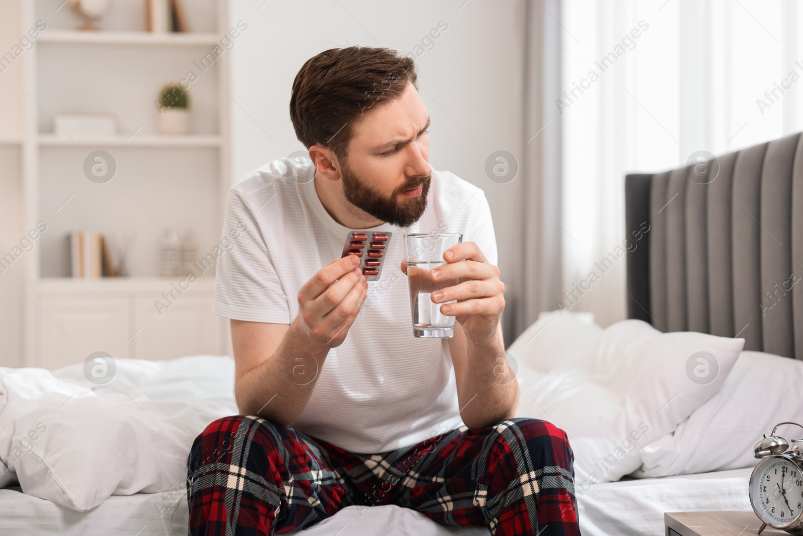 Photo of Young man suffering from headache on bed at morning