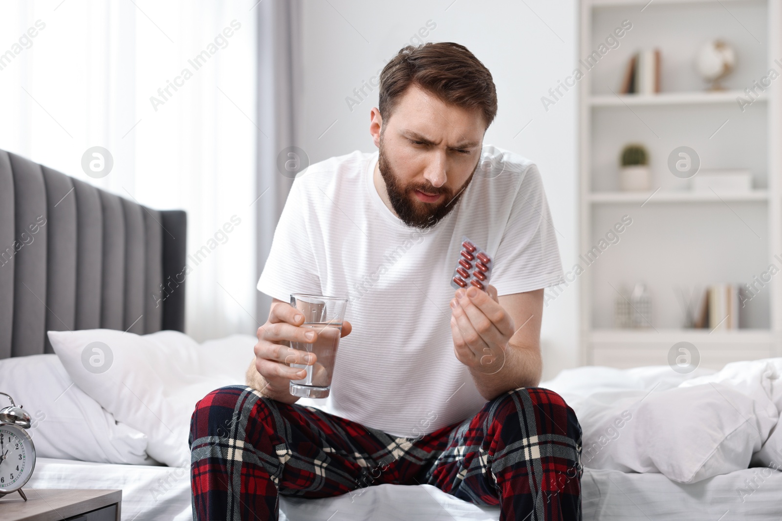 Photo of Young man suffering from headache on bed at morning