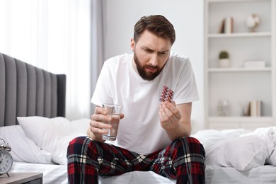 Photo of Young man suffering from headache on bed at morning