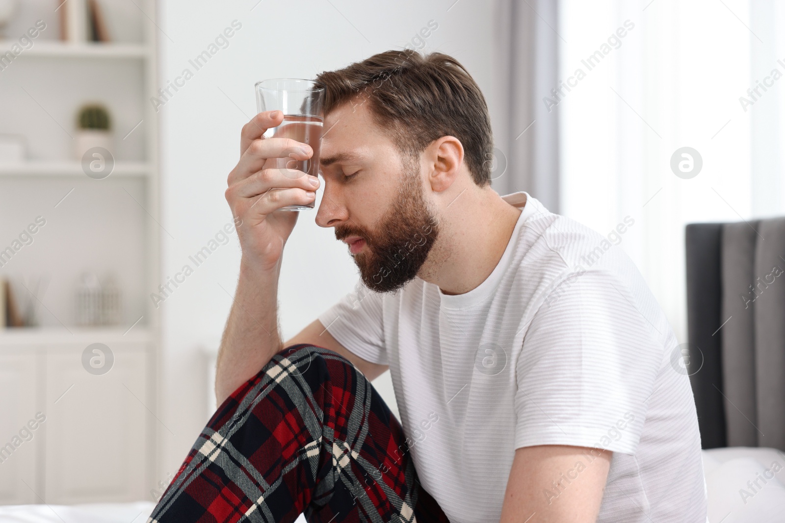 Photo of Young man suffering from headache on bed at morning
