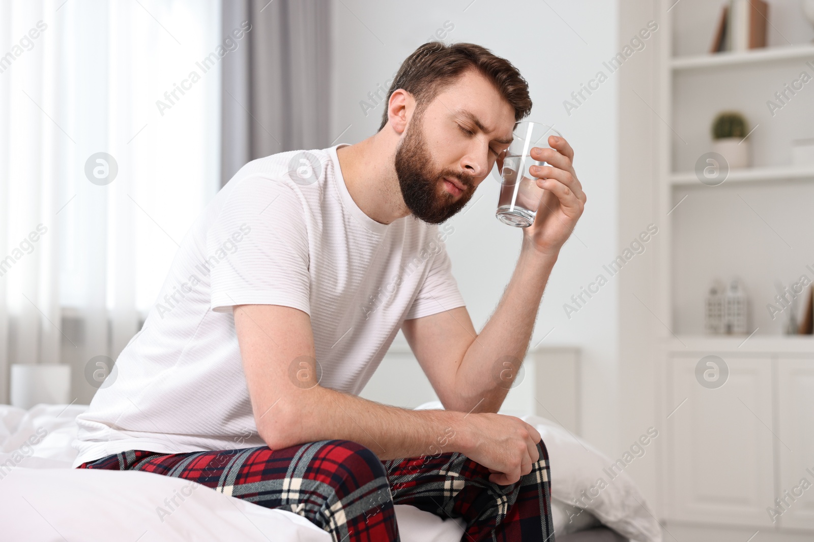 Photo of Young man suffering from headache on bed at morning