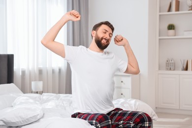 Young man stretching on bed at morning