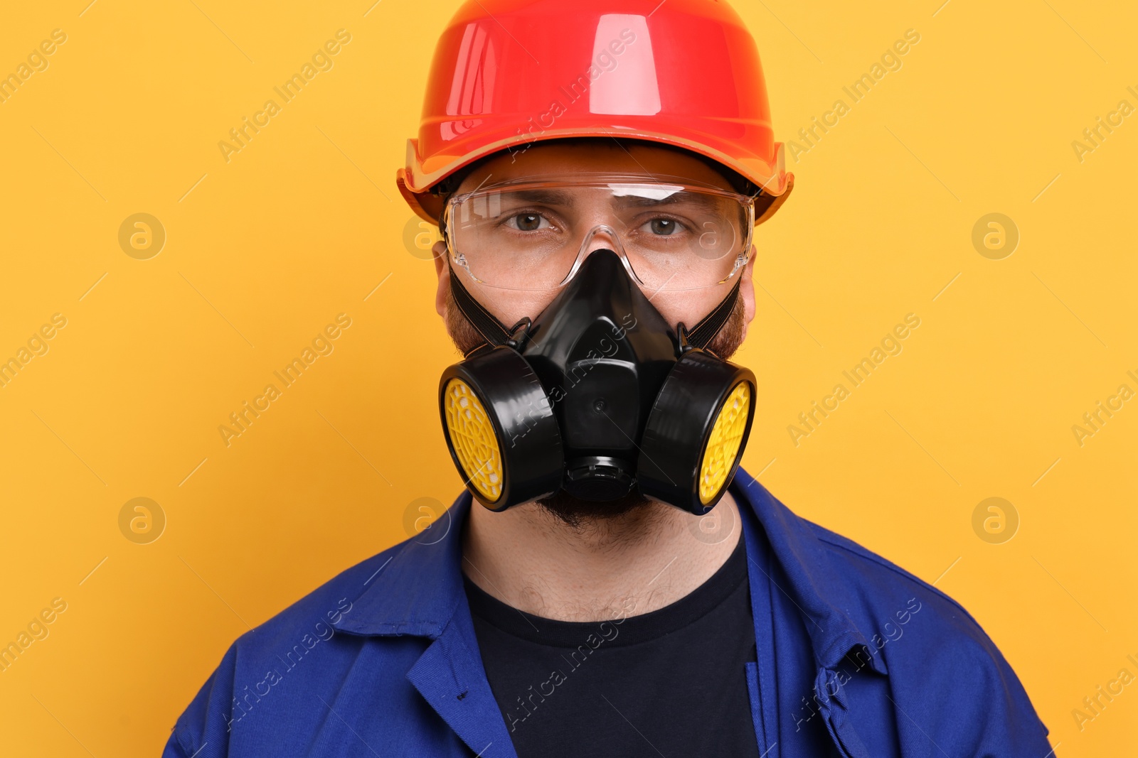 Photo of Man in respirator mask and hard hat on yellow background