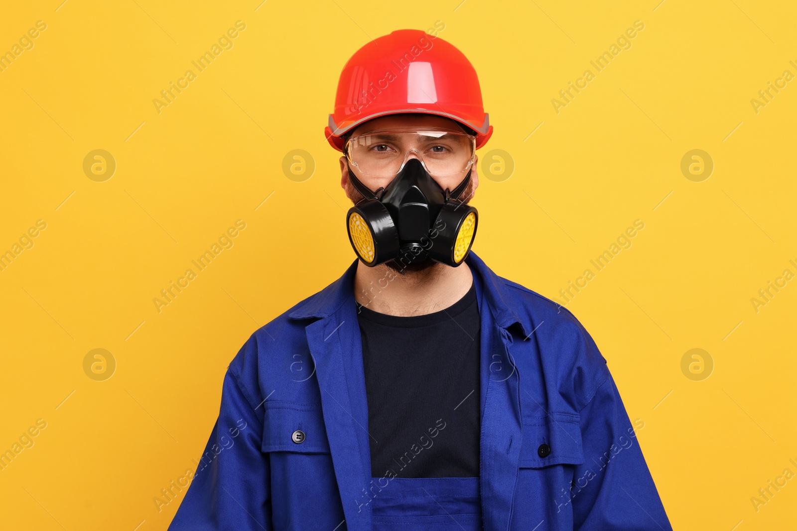 Photo of Man in respirator mask and hard hat on yellow background