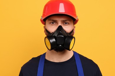 Man in respirator mask and hard hat on yellow background