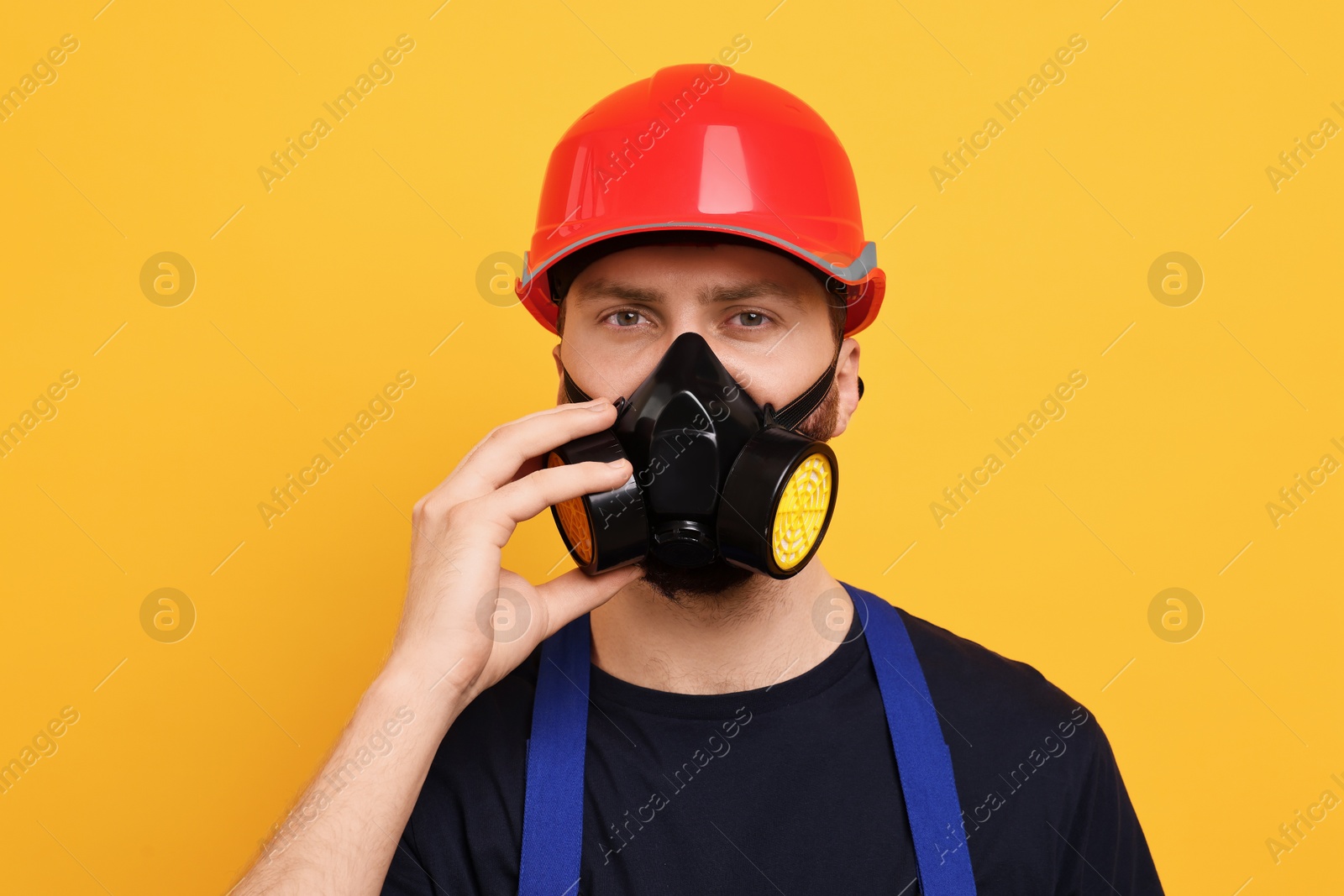 Photo of Man in respirator mask and hard hat on yellow background