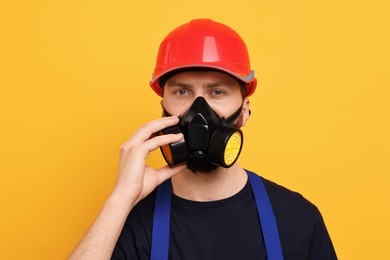 Man in respirator mask and hard hat on yellow background