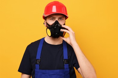 Photo of Man in respirator mask and hard hat on yellow background