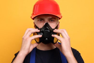 Photo of Man in respirator mask and hard hat on yellow background