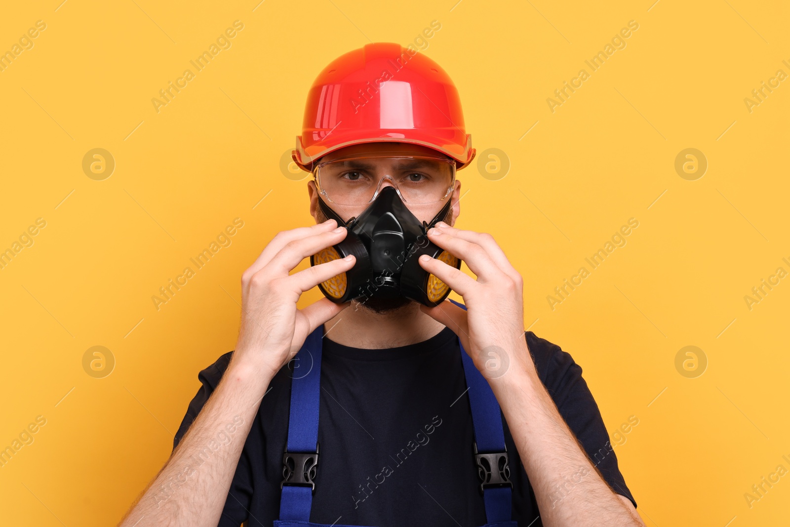 Photo of Man in respirator mask and hard hat on yellow background