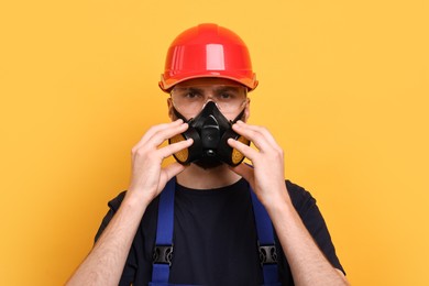 Man in respirator mask and hard hat on yellow background