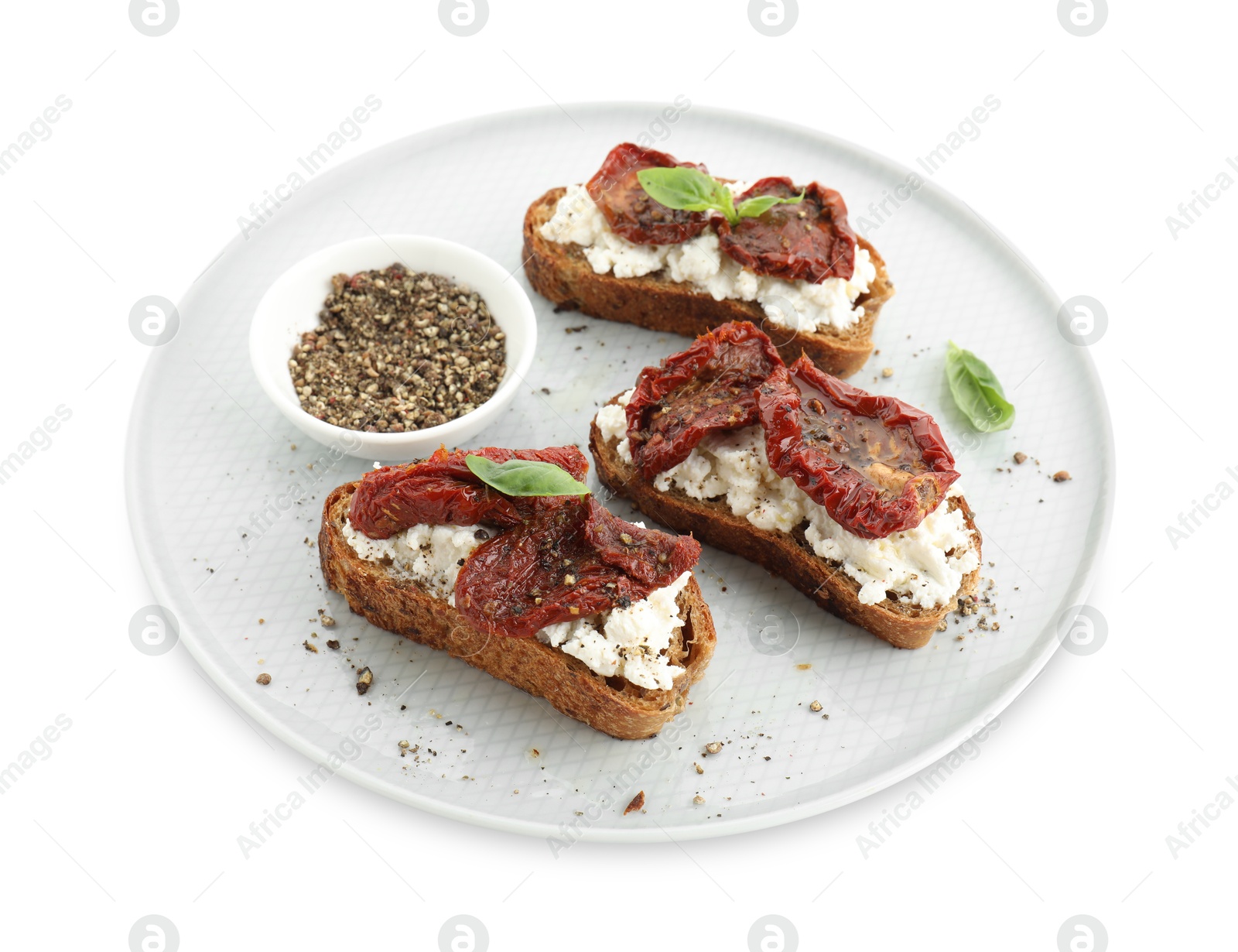 Photo of Delicious ricotta bruschettas with sun dried tomatoes, basil and milled pepper isolated on white