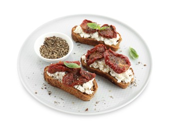 Photo of Delicious ricotta bruschettas with sun dried tomatoes, basil and milled pepper isolated on white