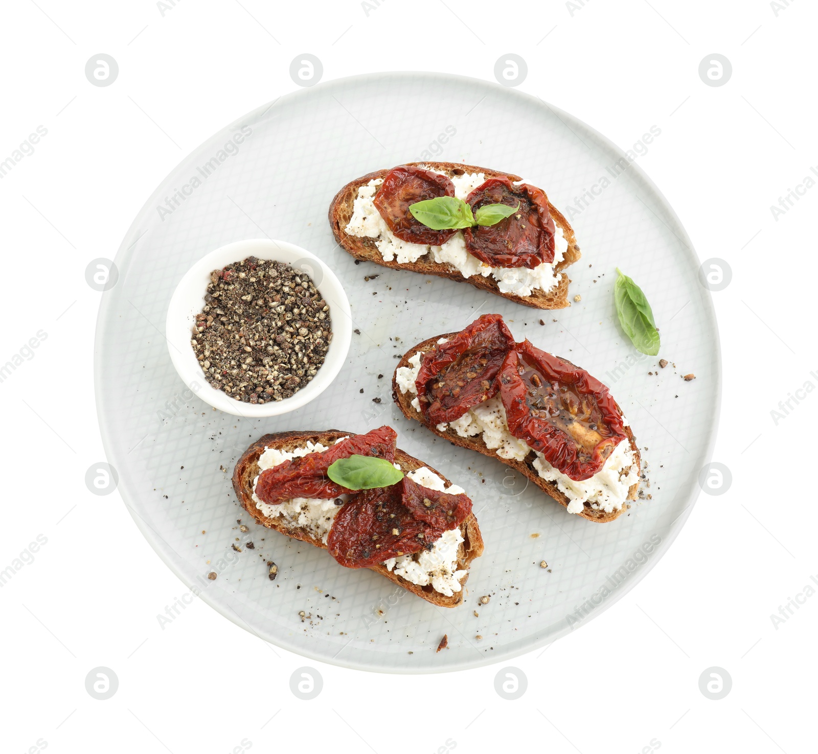 Photo of Delicious ricotta bruschettas with sun dried tomatoes, basil and milled pepper isolated on white, top view