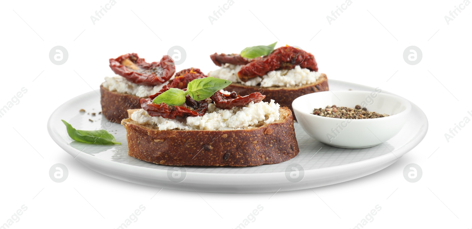 Photo of Delicious ricotta bruschettas with sun dried tomatoes, basil and milled pepper isolated on white